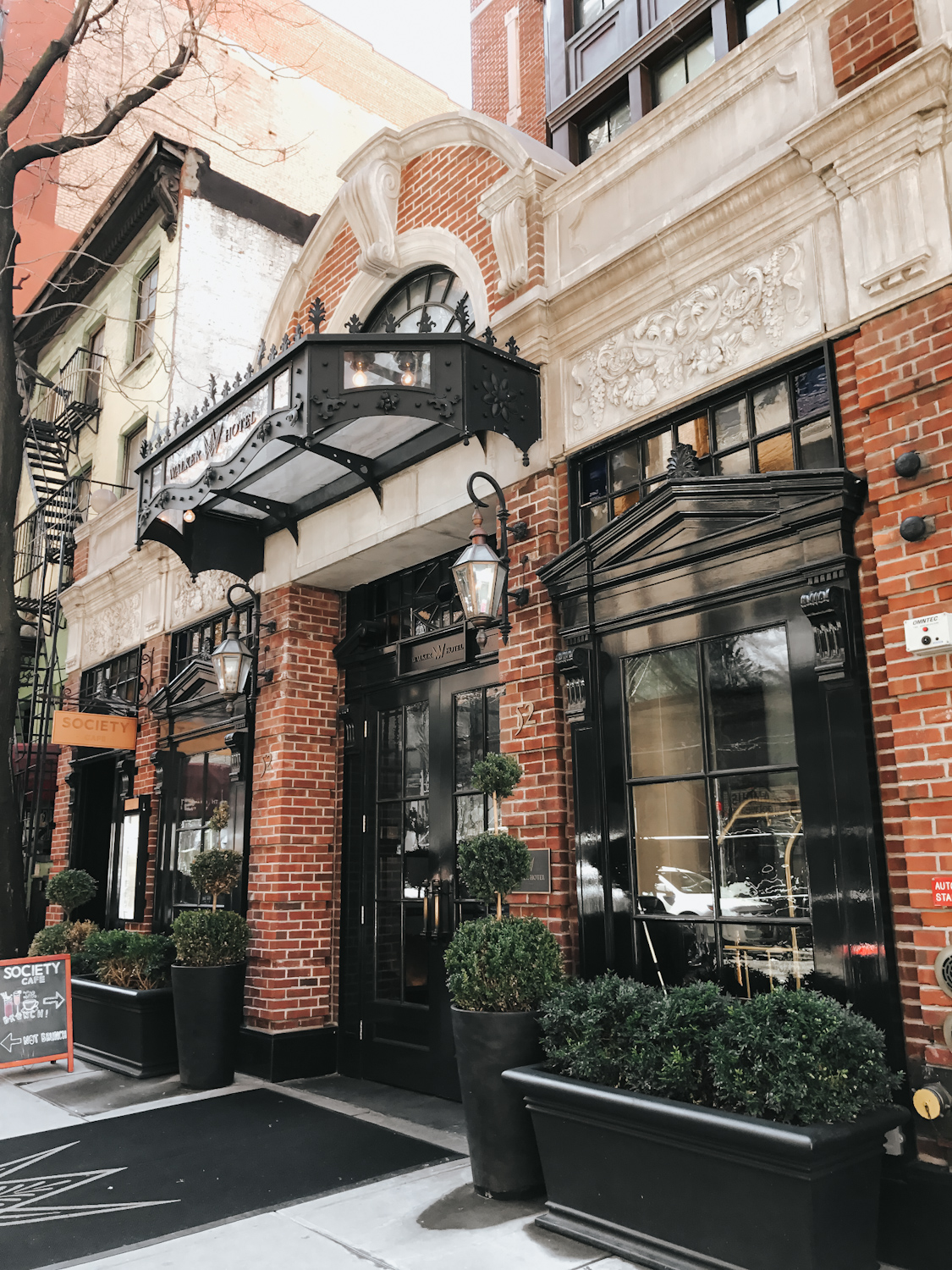 Walker Hotel Greenwich Village exterior entrance with black ironwork awning and gas lanterns New York City